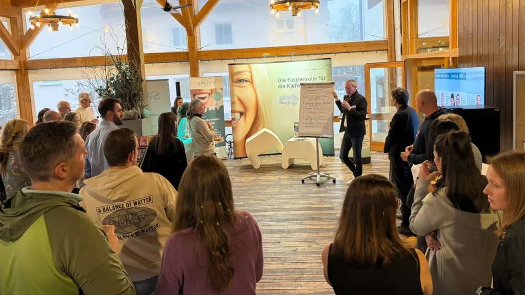 Ein Referent hält vor einem stehenden Publikum einen Vortrag zur Faszienrolle für die Kiefermuskulatur.